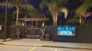 A beach club entrance with a sign for Marau Beach Club, a stone lion statue, and a pathway leading to the beach. - Attic apartment in Vera Beach with beautiful sea and mountain views (Vera Playa)