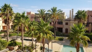 A resort with palm trees, a pool, and buildings with a traditional architectural style. - Attic apartment in Vera Beach with beautiful sea and mountain views (Vera Playa)