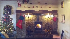 A cozy living room with a stone fireplace, a Christmas tree, and festive decorations.