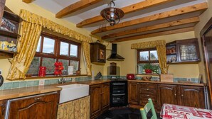 A kitchen with wooden beams, a sink, cabinets, and a dining area with a table.