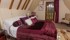 A bedroom with a large bed, a wooden ceiling, a door with glass panels, and a chair in the corner.