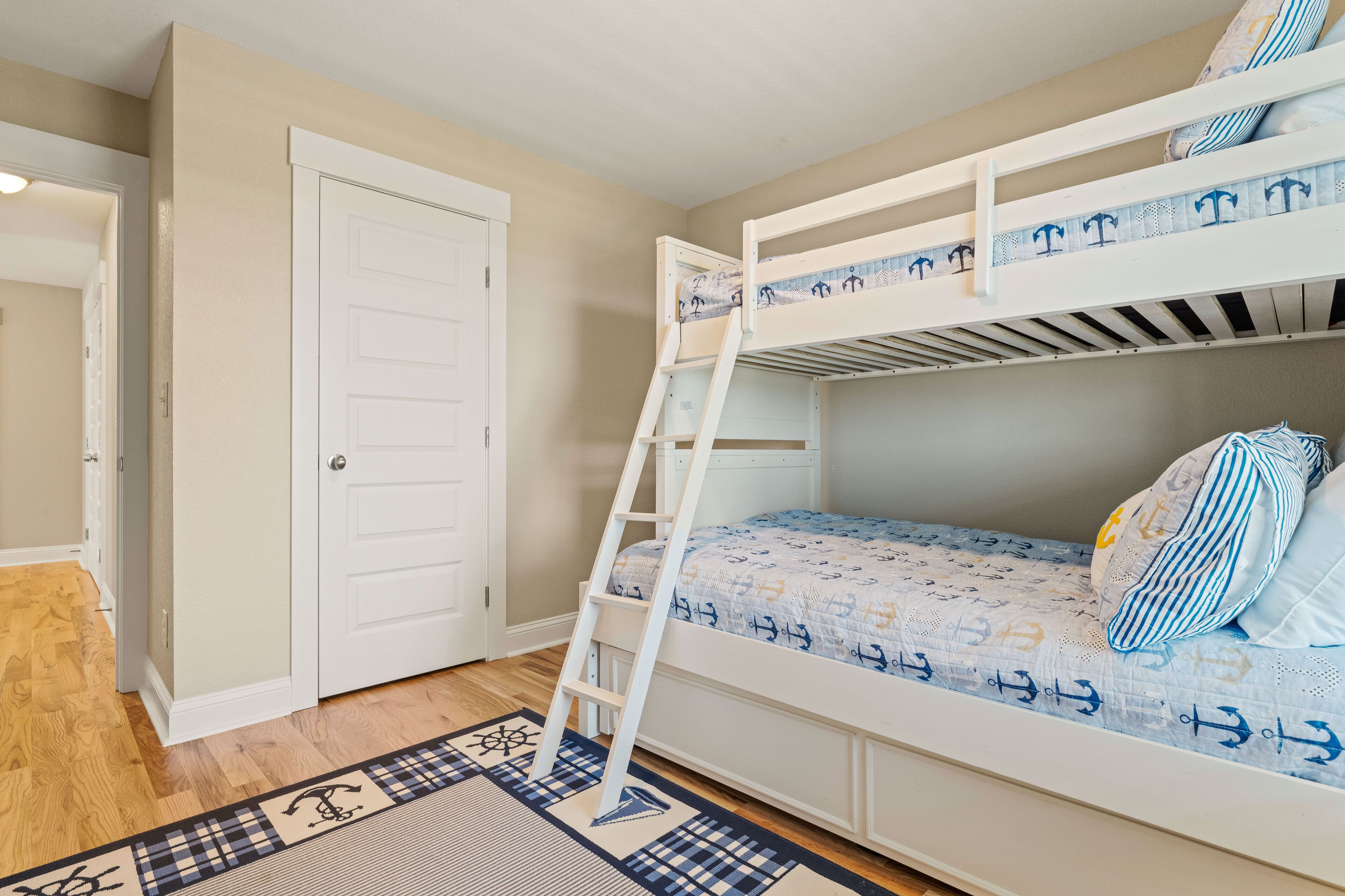 A bunk bed with a ladder, a door, and a patterned rug.