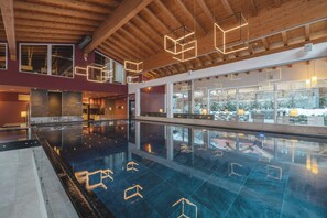 Una piscina techada, una piscina al aire libre, sombrillas