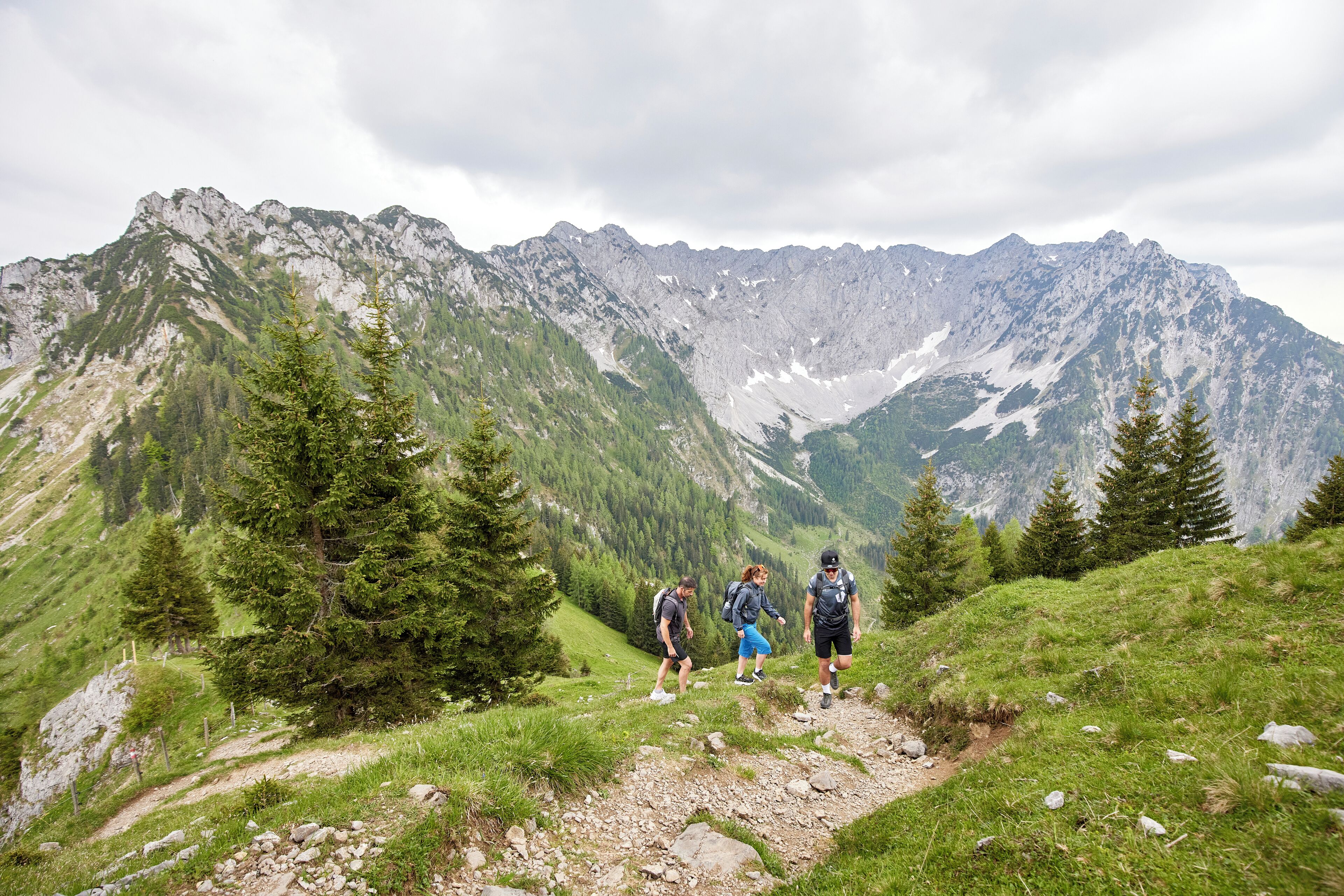 A mountainous hiking trail with rocky terrain and sparse vegetation.