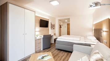 Una habitación de hotel moderna con cama, sofá, escritorio, armario y televisor.