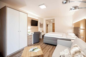 Una habitación de hotel moderna con cama, sofá, escritorio, armario y televisor.