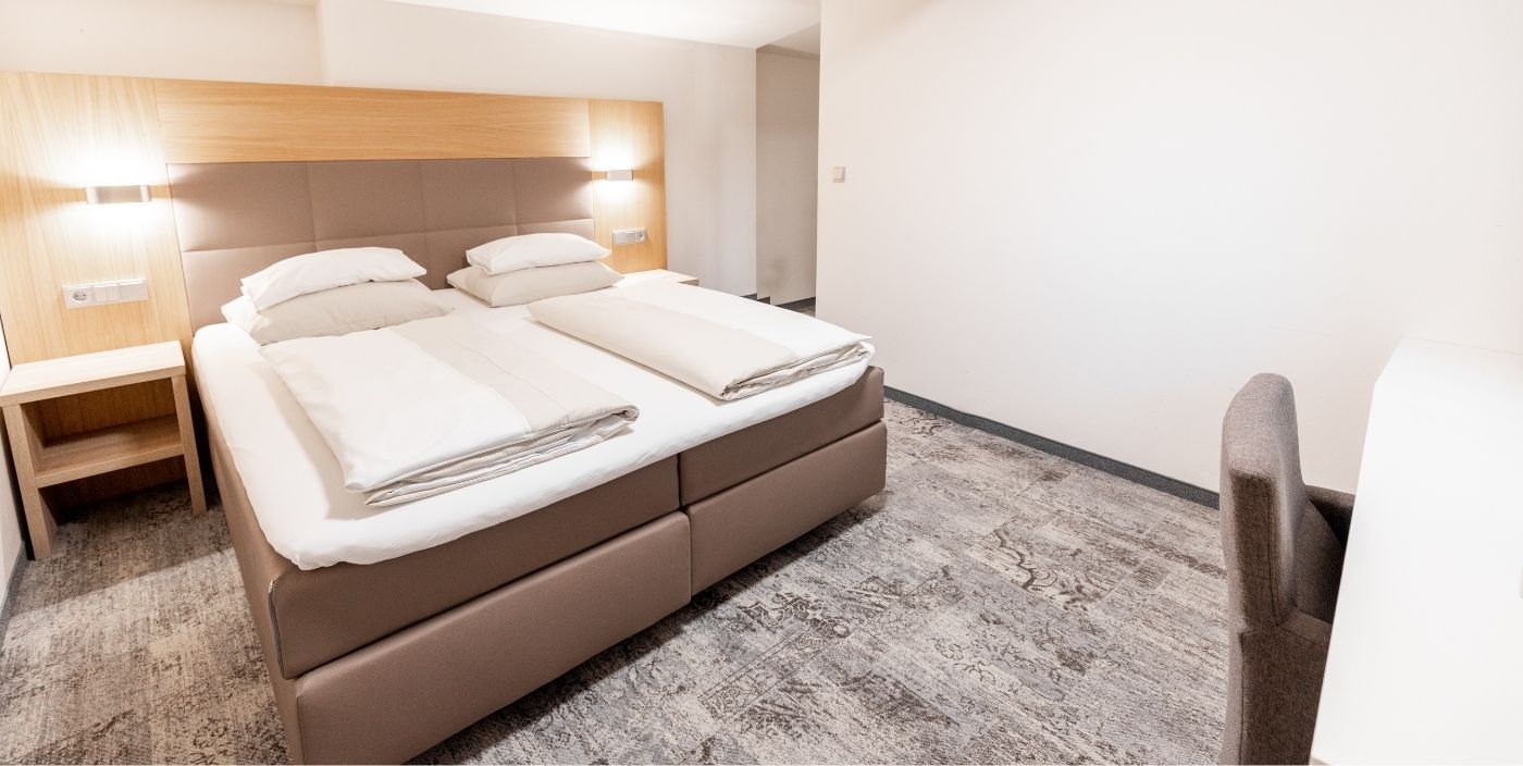 A hotel room with a large bed, bedside tables, and a chair.