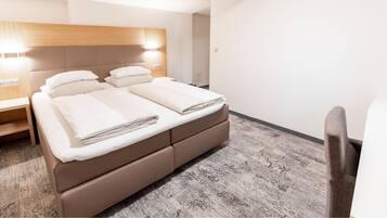 A hotel room with a large bed, bedside tables, and a chair.
