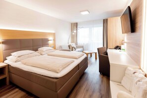 Habitación de hotel con una cama grande, un escritorio, una silla, un televisor y un área de baño.