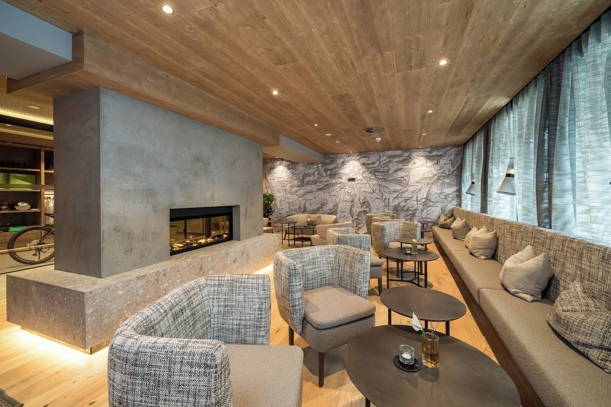 Eine moderne Lounge mit Kamin, Sitzgelegenheiten und einer Wand mit Karten.