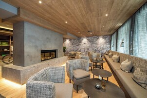 Un área de estar moderna con chimenea, asientos y una pared decorada con mapas.