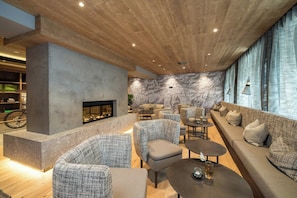 Un área de estar moderna con chimenea, asientos y una pared decorada con mapas.