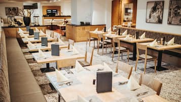 A restaurant with multiple tables, each set with cutlery and napkins.