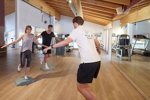 A gym with wooden floors and exercise equipment.