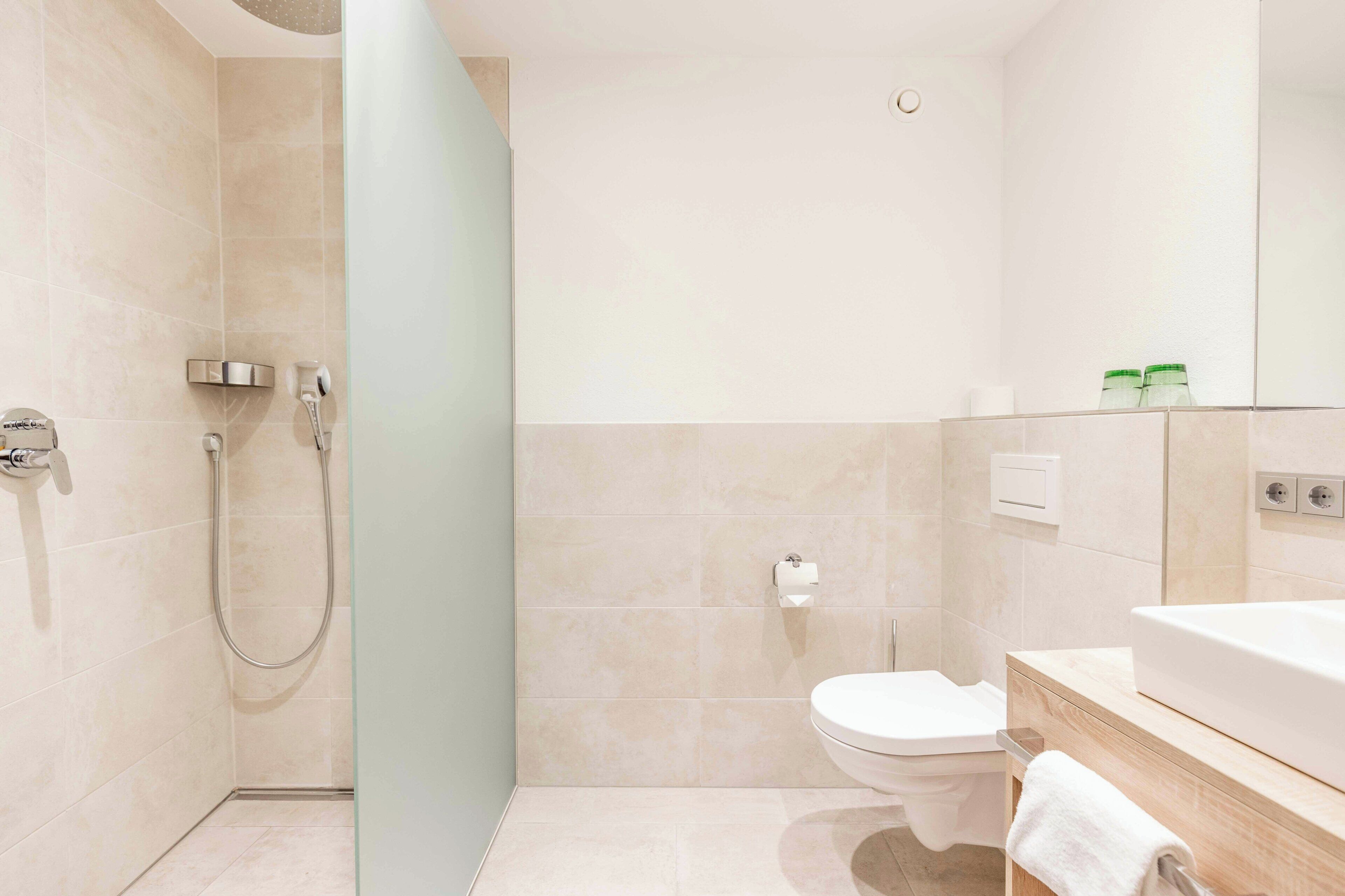 A modern bathroom with a shower, toilet, and sink.