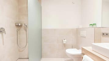 A modern bathroom with a shower, toilet, and sink.