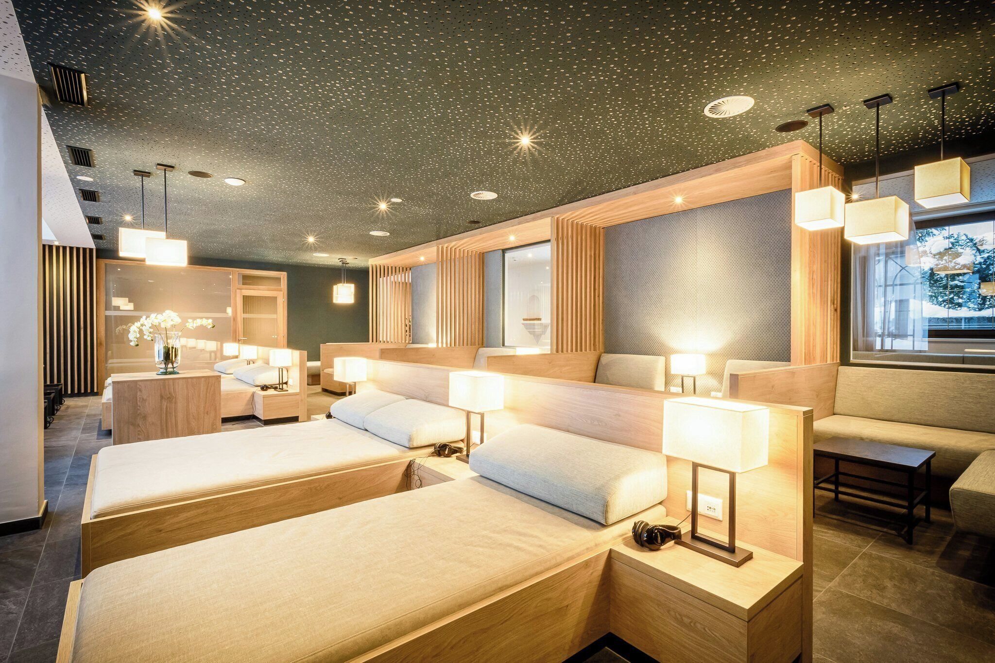 A hotel room with three beds, a sofa, a small table, and a window with a view.