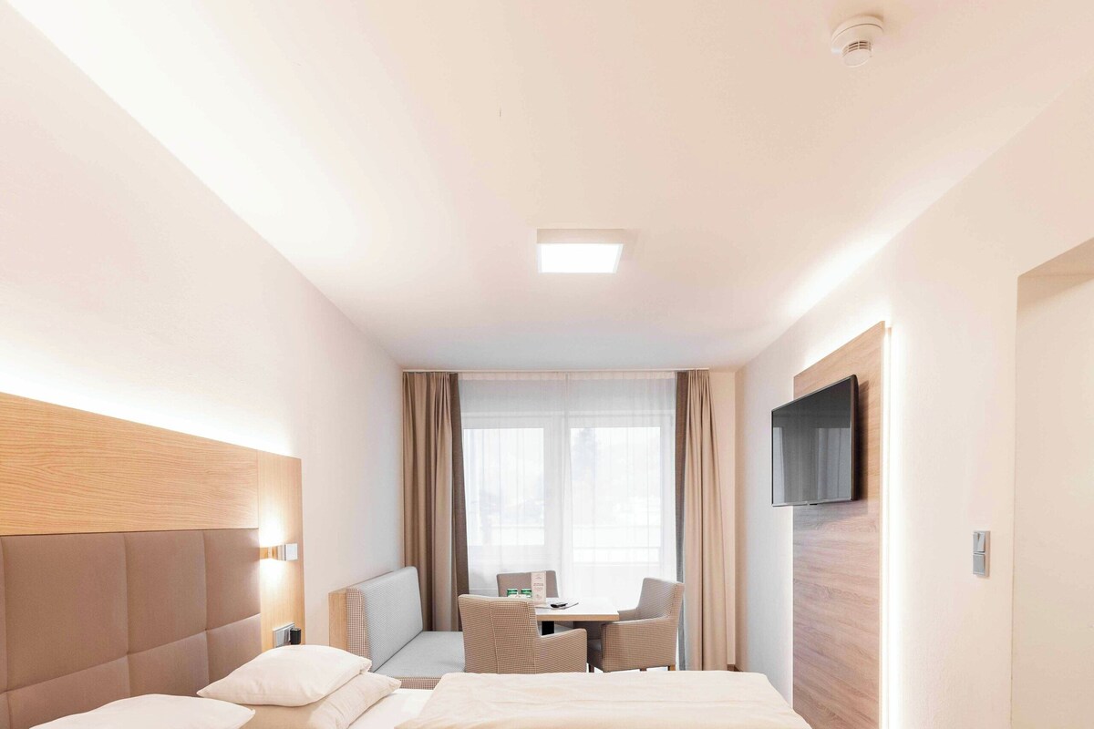 Una habitación de hotel con una cama grande, un escritorio y un televisor.