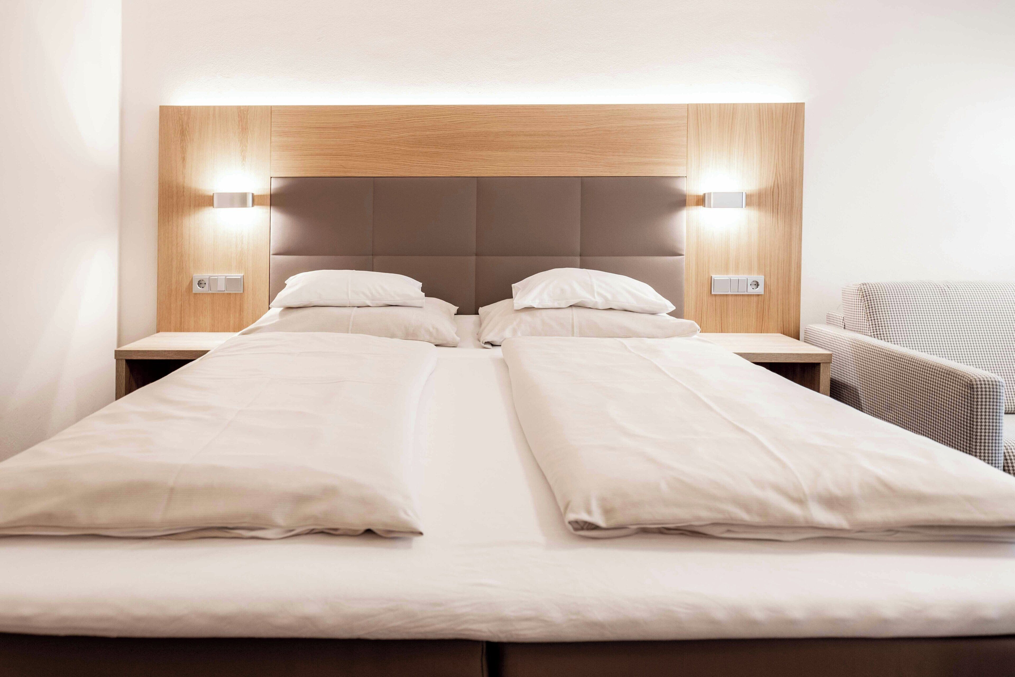 Un lit double avec une tête de lit en bois, deux tables de chevet et une couverture à carreaux.