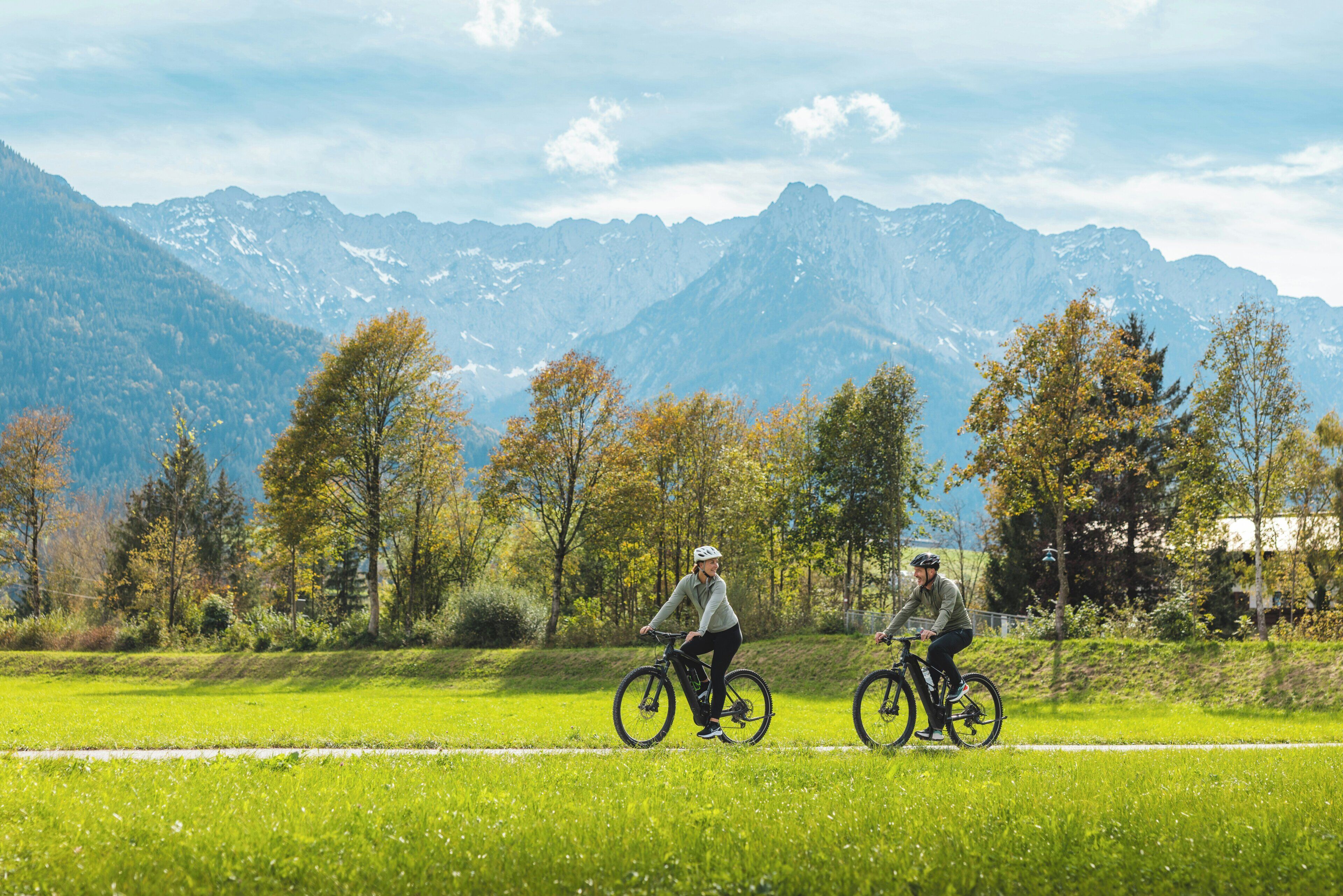 Zwei Radfahrer auf einem Weg vor einer Bergkulisse.