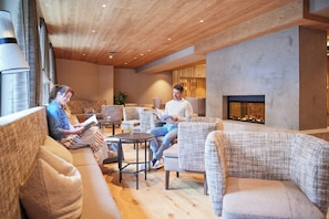 Un salón moderno con sofás, chimenea e iluminación empotrada en el techo.