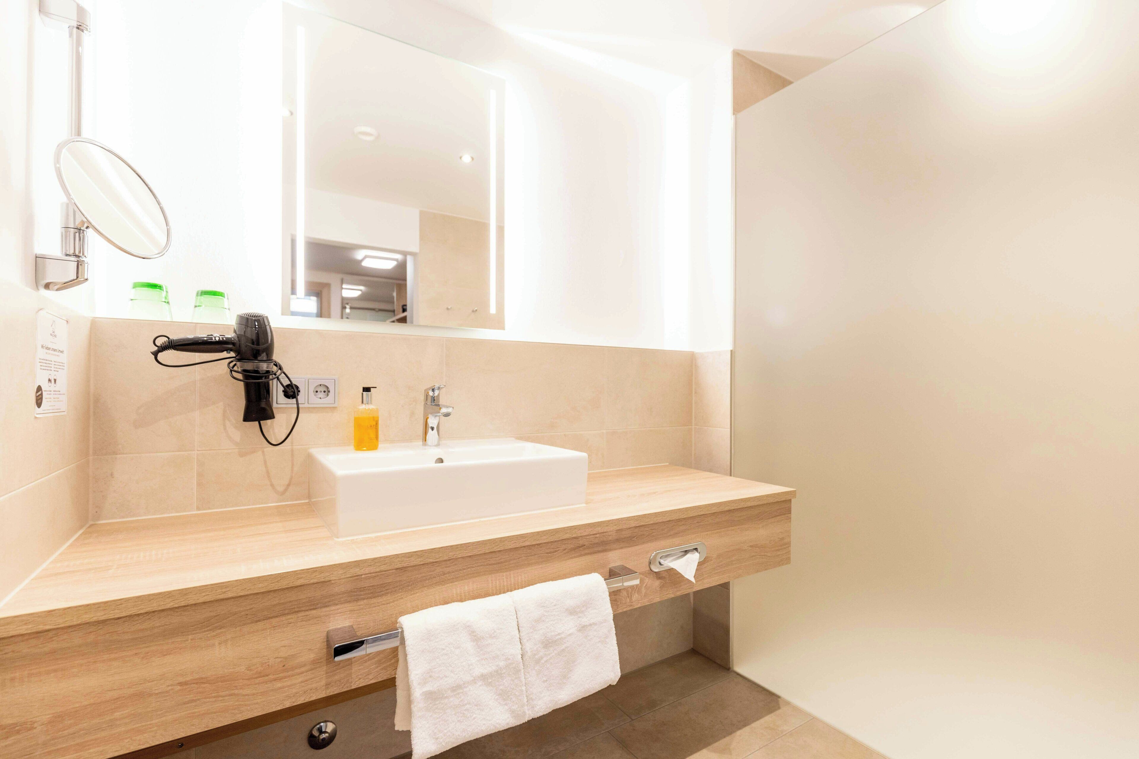 Une salle de bain équipée d’un lavabo, d’un miroir, d’un porte-serviettes et d’un savon.