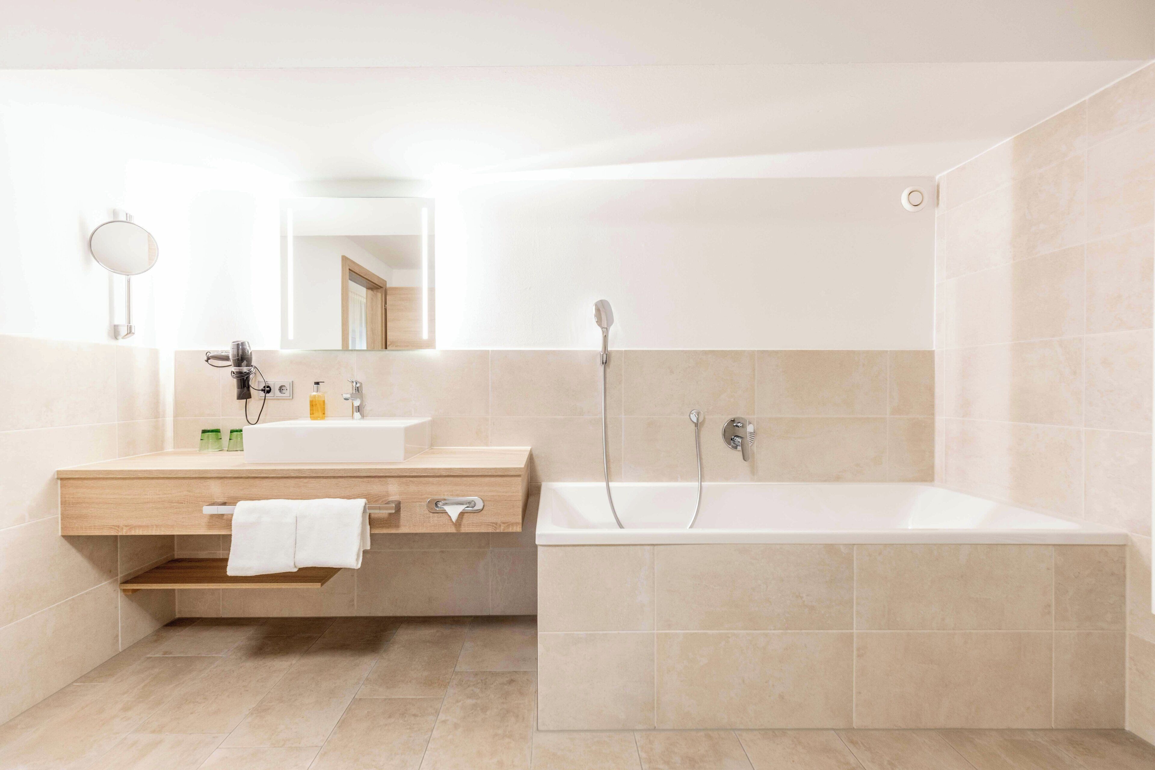 A modern bathroom with a large bathtub, a sink with a mirror, and a towel rack.