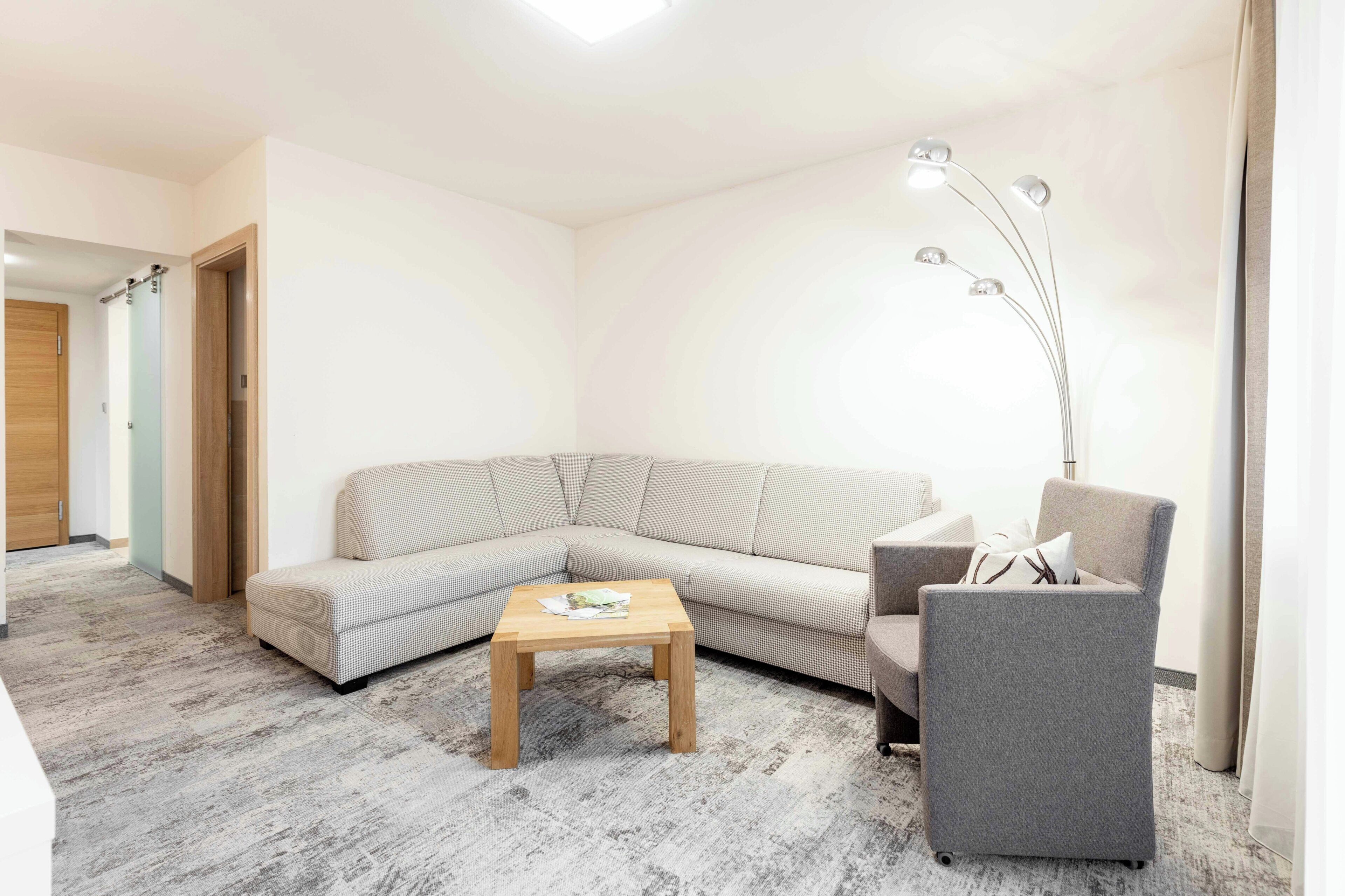 Una sala moderna con un sofá modular, una mesita de madera y un sillón gris.