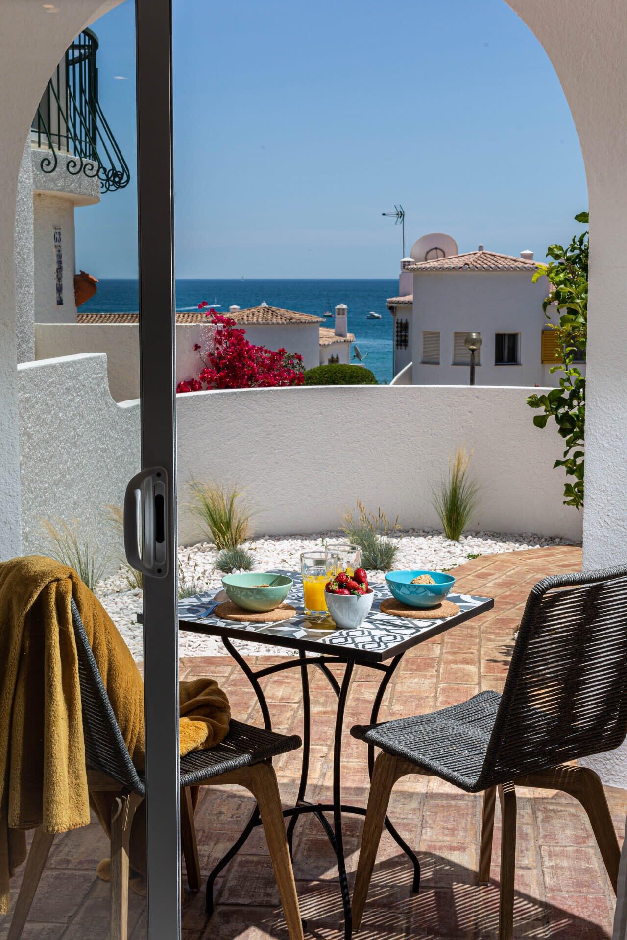Eine Terrasse mit Frühstückstisch, mit Blick auf die Küste.