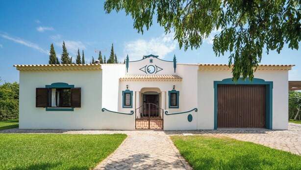 A two-story house with a tiled roof, a central entrance with a decorative arch, and a large garage door.