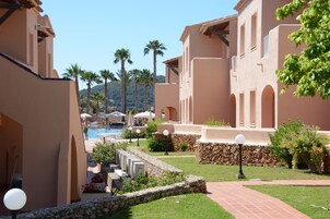 A resort with a swimming pool, palm trees, and a stone pathway.