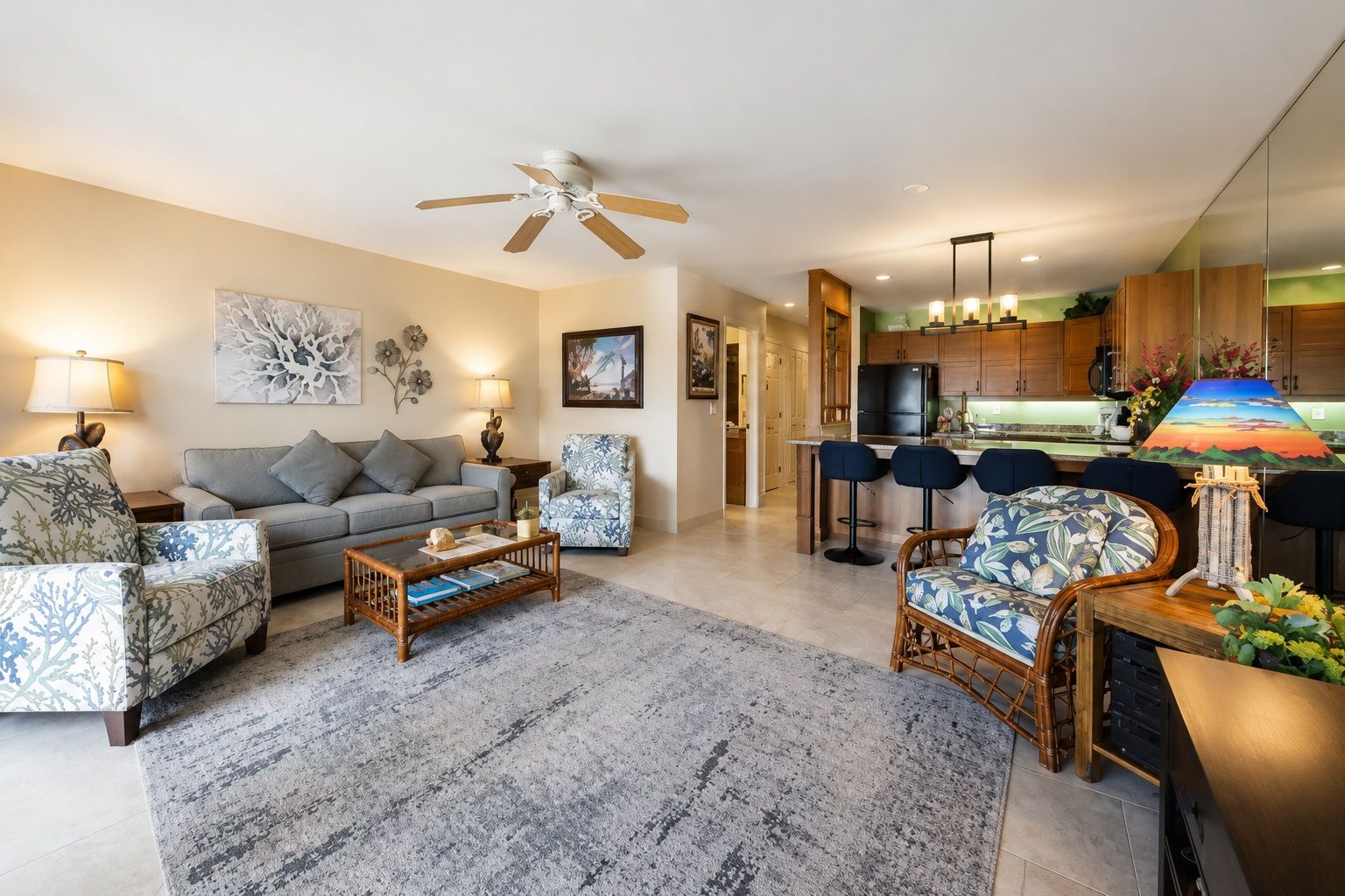 A modern living room with a sofa, armchairs, a coffee table, and a dining area with bar stools.