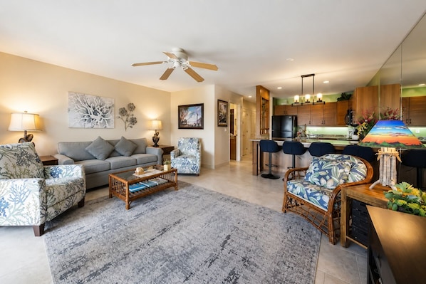 A modern living room with a sofa, armchairs, a coffee table, and a dining area with bar stools.