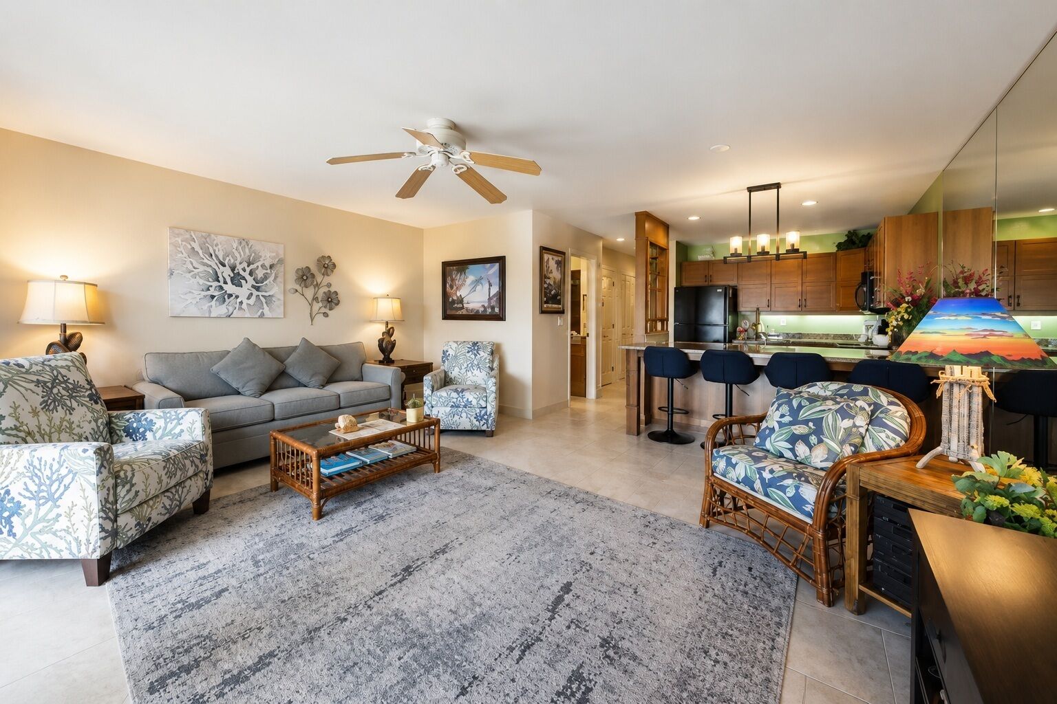 A modern living room with a sofa, armchairs, a coffee table, and a dining area with bar stools.