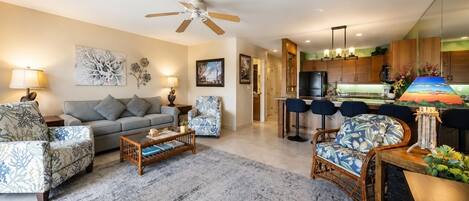 A modern living room with a sofa, armchairs, a coffee table, and a dining area with bar stools.