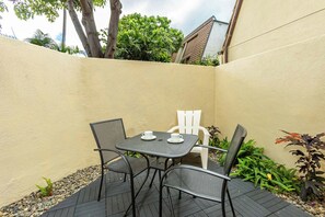 A patio with a table and four chairs, surrounded by a low wall and various plants.
