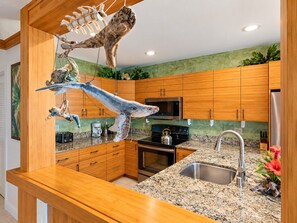 A kitchen with wooden cabinets, a stainless steel sink, a microwave, and a stove.