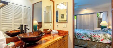 A bathroom with a wooden vanity, two large mirrors, and a vessel sink.