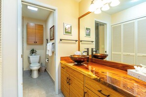A bathroom with a wooden vanity, a large mirror, and a bowl sink.