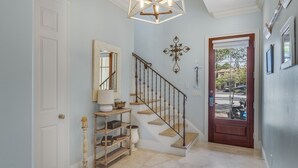 Una escalera con barandilla de madera y peldaños color beige, que conduce a una puerta con panel de vidrio.
