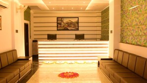 A hotel reception area with a reception desk, two sofas, a patterned wall, and a carpeted floor. - Hotel Suraj Palace (Bhopal)