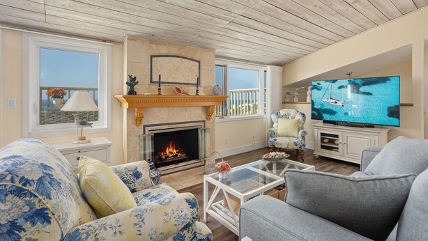 En stue med pejs, tv og balkon med udsigt.