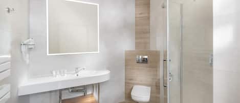 A modern bathroom with a large mirror, a sink, a toilet, and a shower.