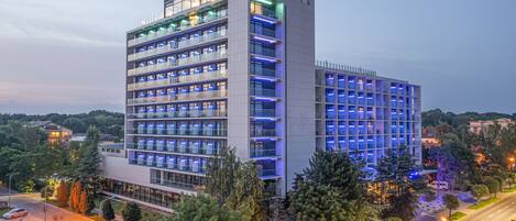 A multi-story hotel with a modern design, featuring balconies on each floor and a prominent entrance.
