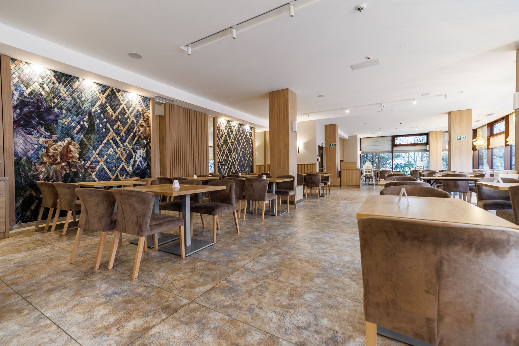 A spacious restaurant with high ceilings, modern lighting, and a mix of wooden and upholstered furniture.