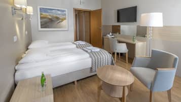 Une chambre d’hôtel avec un lit, un bureau, une chaise, une télévision et un tableau au mur.
