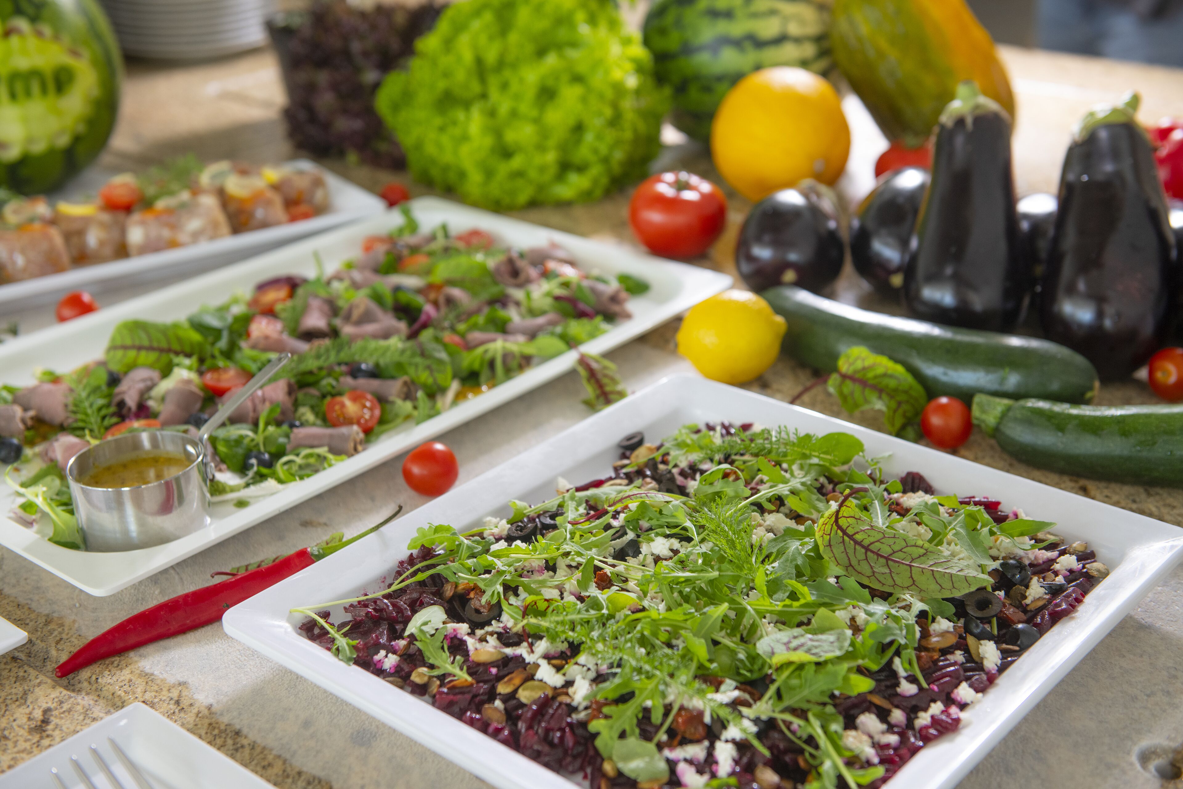 Una variedad de platos en una mesa de buffet, con ensaladas y verduras.