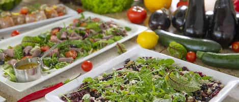 A variety of dishes on a buffet table, including salads and vegetables.