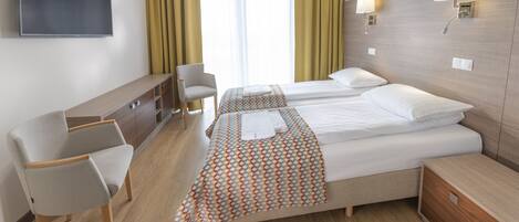 Una habitación de hotel con dos camas, televisión, escritorio y silla.