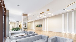 A modern waiting area with grey sofas, wooden flooring, and contemporary lighting fixtures. - Olymp IV Spa & Wellness (Kolobrzeg)